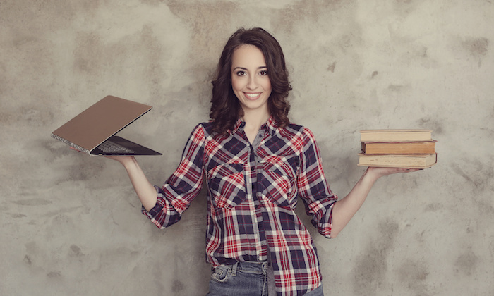Cute woman balancing laptop and books