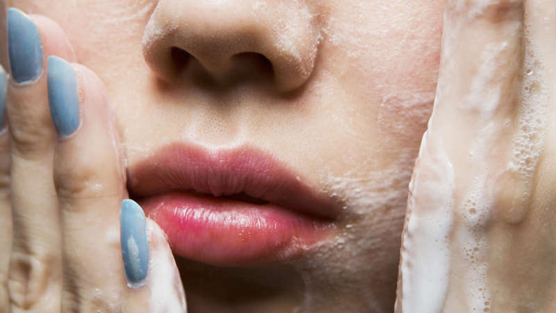 Young woman washing face, close-up of mouth