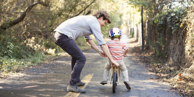 Father teaching son to ride bicycle