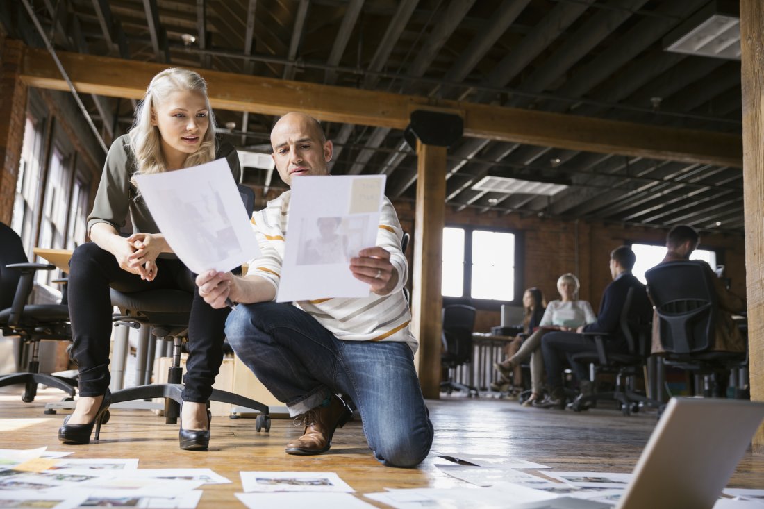 Business people reviewing proofs on floor in office